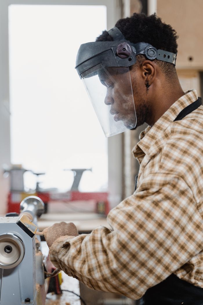 Craftsman using a lathe in a woodworking workshop, focusing on precision and safety.